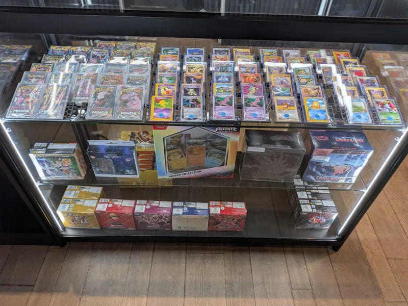 Pokémon singles in top loaders and sealed One Piece and Pokémon product in the glass display cabinet